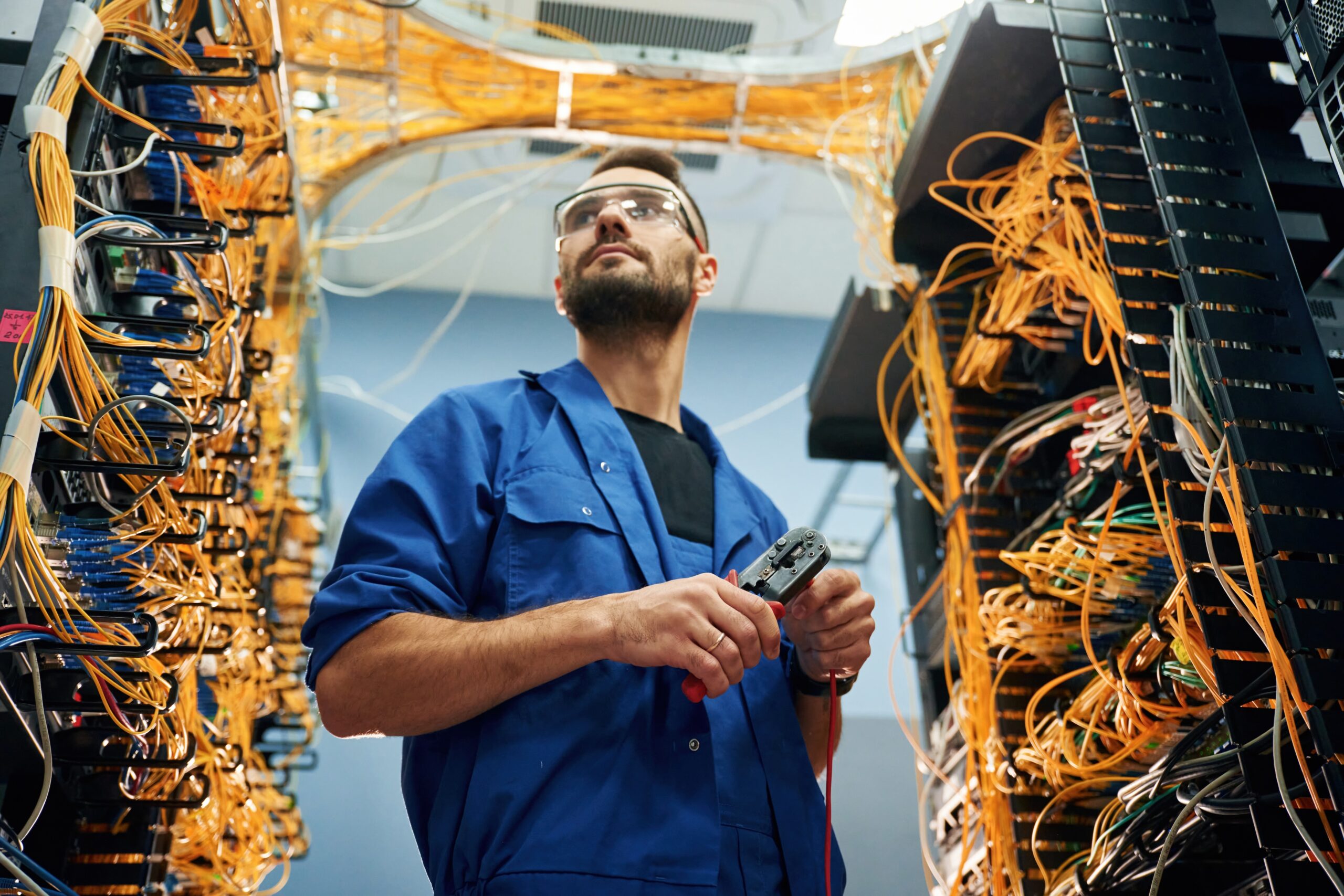 Young man is working with internet equipment in server room.