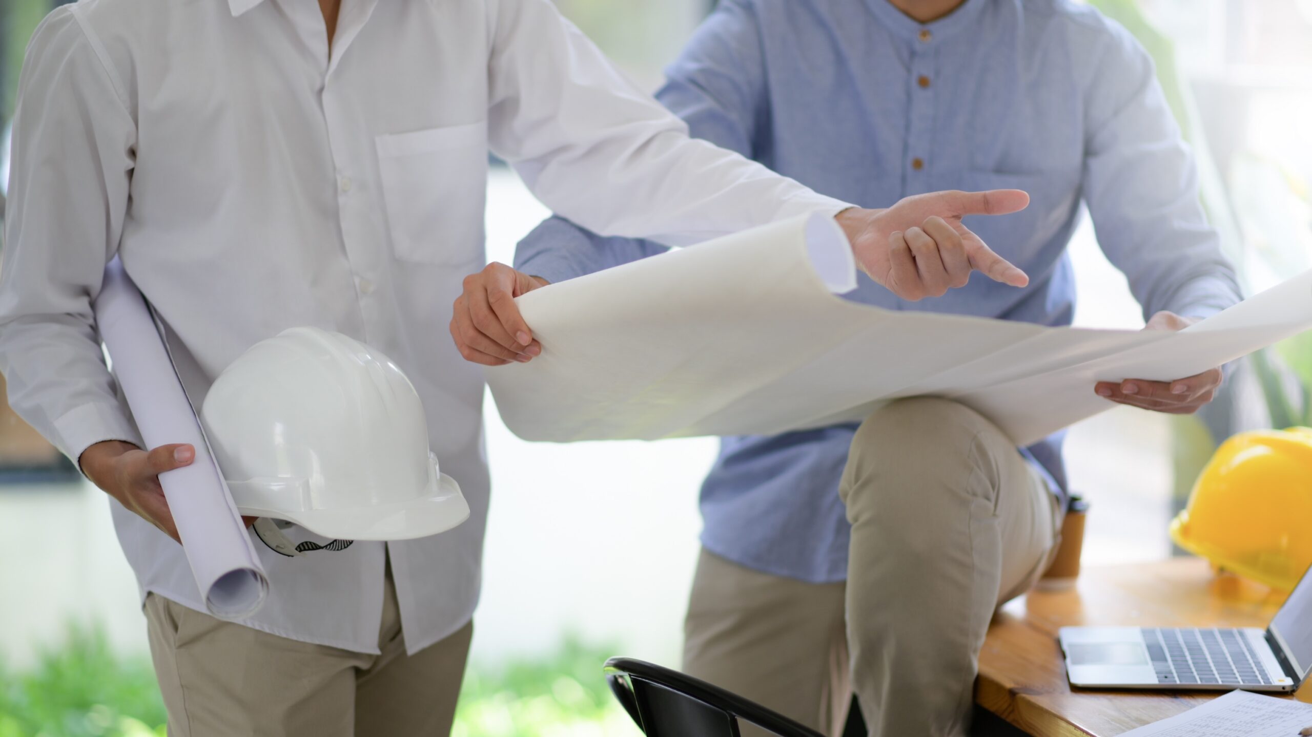 IT company working with General contractor on blueprints, closeup of blueprints and two people discussing